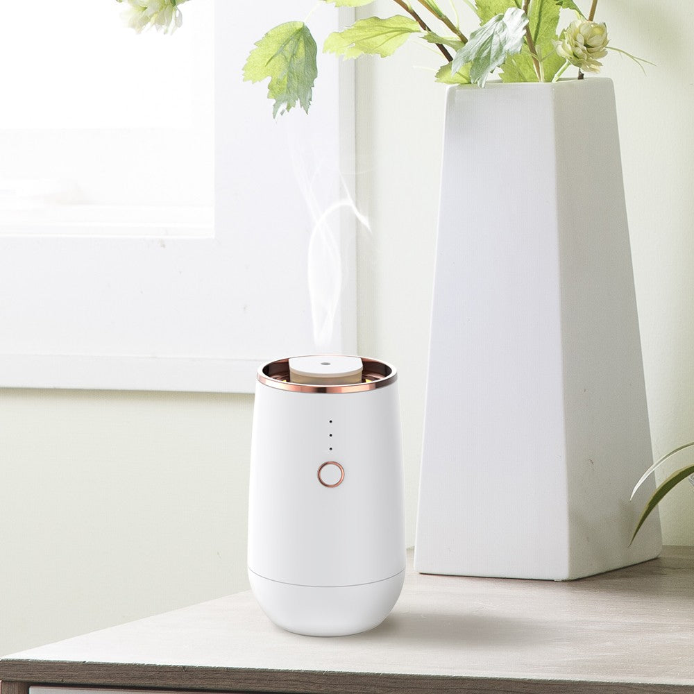 WSNUEEE A603 cordless waterless aroma diffuser standing on a table at home, releasing a fine cold-air mist with its ambient light glowing