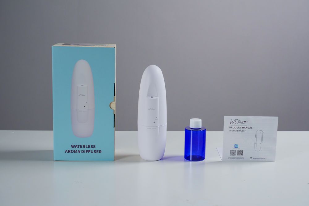 WSNUEEE AE103 retail box with the diffuser, a 100 mL oil bottle and the printed user manual laid out beside it